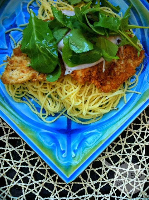 An overhead shot of Chicken Bellagio on a blue plate topped with arugula